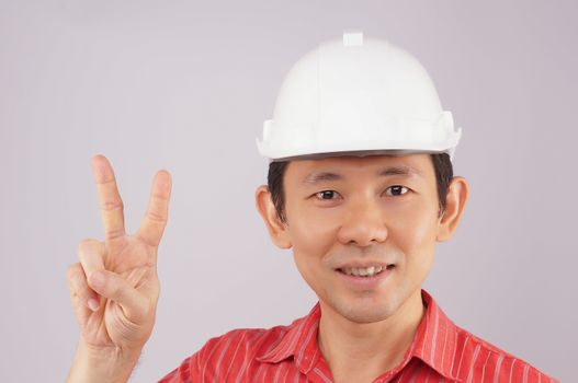 Engineer wear red shirt and white engineer hat make signal by victory on white background.