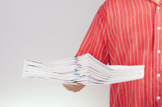 Man hold pile overload of report with colorful paper clip have blur man with red shirt on white background.
