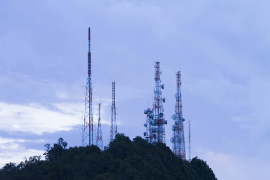 The tall antenna with the mountain and the sky for background.