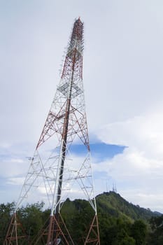 The tall antenna with the mountain and the sky for background.