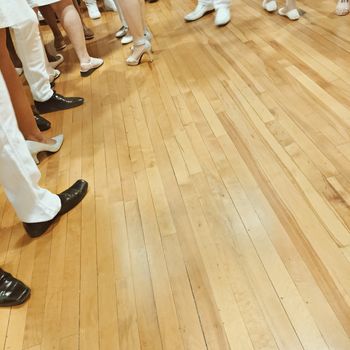 People's feet on parquet floor, with lots of copy space.