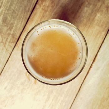 Glass of unfiltered seasonal beer on a wooden bar table. View from top.