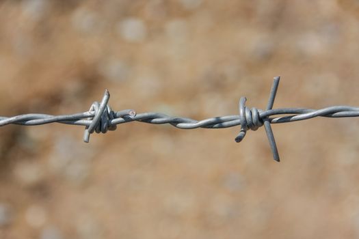 closeup barbed fence with ground on background