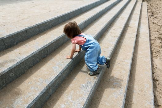 Baby girl in blue cloth creep up on the stairs