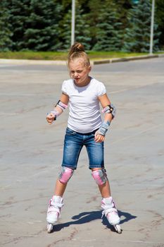 Learning girl on roller skates in summer