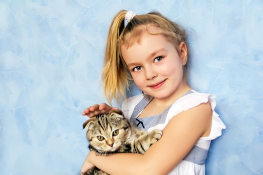 Blond girl with grey kitty on blue