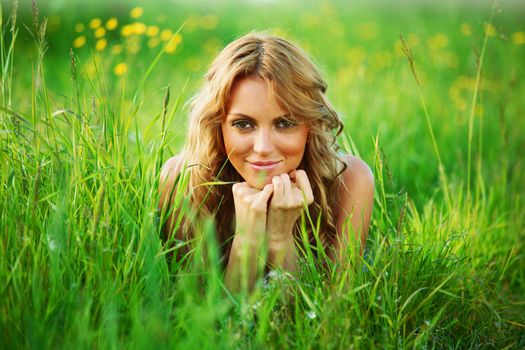 blonde young woman lays on green grass