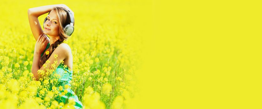 woman listening to music on oilseed field