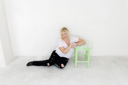 Blond woman in white sitting on the floor inside empty room