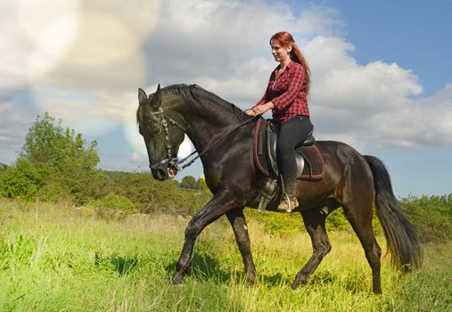 young riding girl and her black stallion in nature