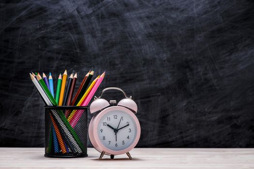 School and office supplies and apple in front of blackboard.