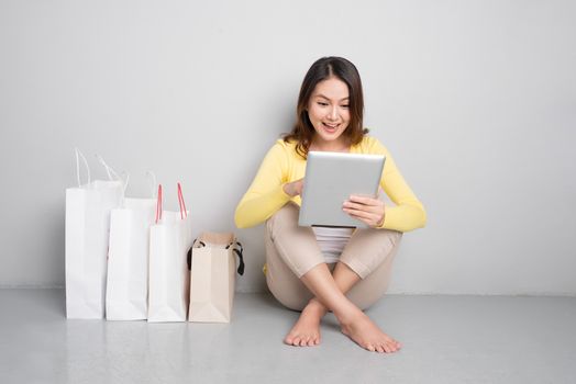 Young asian woman shopping online at home sitting besides row of shopping bags