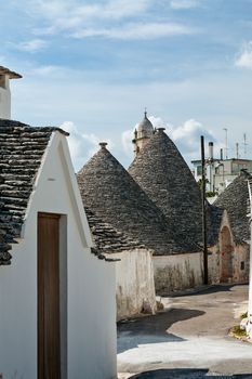 Typical street with Trulli houses under a blue sky in Alberobello, Puglia, Italy