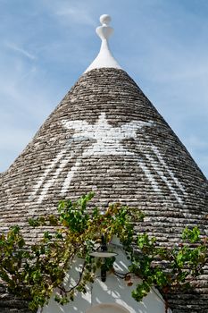 Symbol in the Trullo conical rooftop in Alberobello under a blue sky, Puglia, Italy