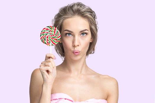 Portrait of funny cute woman with lollipop over pink background