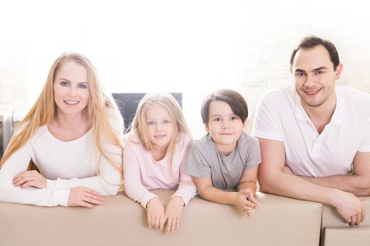 Family of four people with children relaxing on sofa