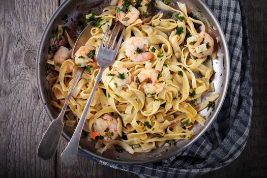 Tagliatelle with shrimps on the pan with fork and spoon