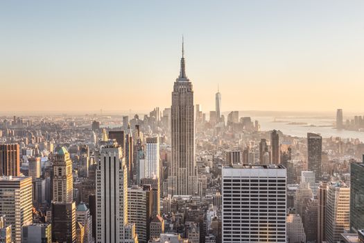 New York City. Manhattan downtown skyline with sun illuminated Empire State Building and skyscrapers at sunset.