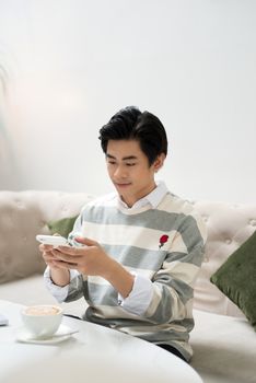 Asian young man taking photo of coffee cup during coffee break