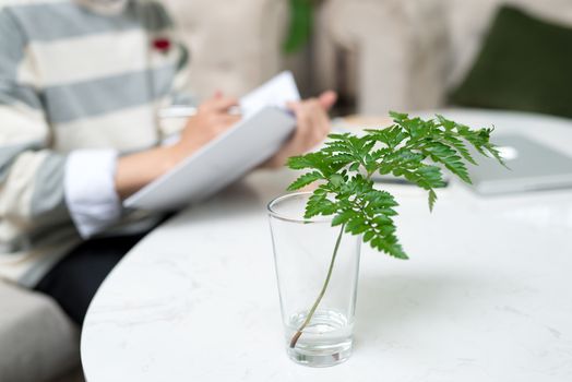 Asian entrepreneur reading book during coffee break with focus on plant.