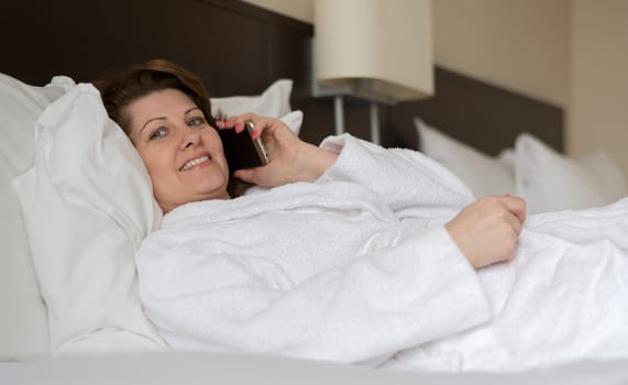 Woman in bathrobe talking on the phone in the hotel room