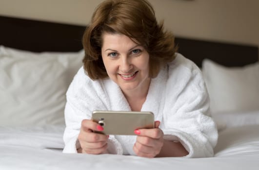 A woman in a bathrobe wears a telephone in the hotel room