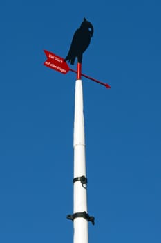 Ship mast with stylized bird and wind flag and the german words for all the best in every way