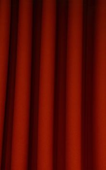 Heavy dark red pleated textile felt curtain background with portiere drape folds, side view close up