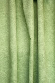 Heavy light green pleated felt textile curtain background with portiere drape folds, side view close up