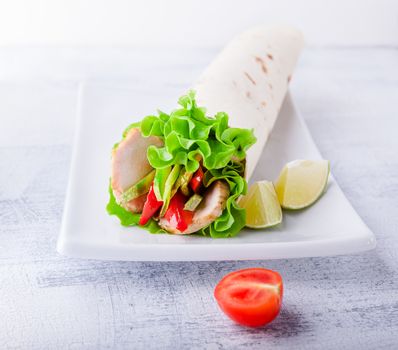 Sandwich wrap with garden salad, chicken, lettuce and tomato in a whole wheat tortilla 
