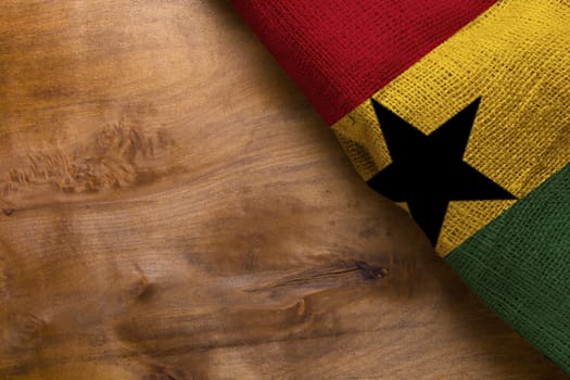 Three-color flag of Ghana on a wooden surface.