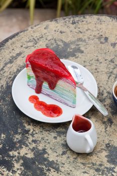 crape cake rainbow and hot espresso coffee in garden side home. crape cake with strawberry sauce