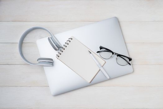 Notepad and computer keyboard on white table with headphone. View from above