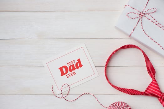 Happy Father's Day with striped tie on wooden background. Greetings and gift box