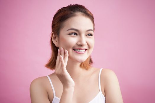Portrait of a beautiful smiling young woman with natural make-up. Skincare, healthcare. Healthy teeth. Studio shot. Isolated on Pink Background.
