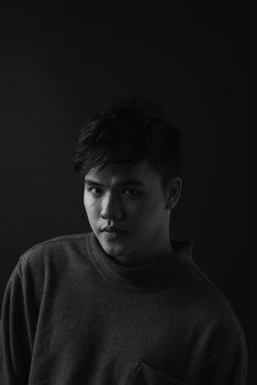 Young asian man's portrait against black background