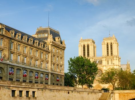 View of the west facade of the Cathedrale Notre-Dame de Paris and part of the building of Police prefecture from the Seine in the spring evening
