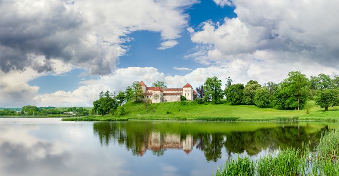 Svirzh Castle built in the 15th century on the lake bank after spring thunderstorm in Lviv region, Ukraine 
