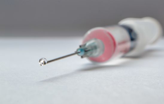 Drop on syringe needle, with red medicament in it