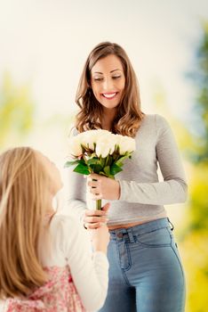 Cute daughter giving her mother bouquet white roses for Mother's Day. Selective focus. Focus on background, on mom.