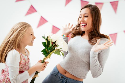 Cute daughter giving her mother bouquet white roses for Mother's Day. 