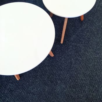 Round white tables on carpet floor. Modern furniture.