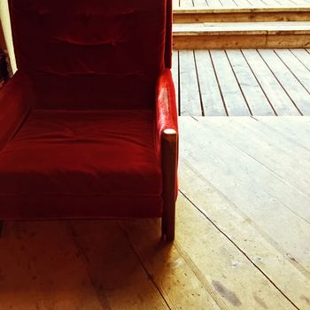 Rustic interior with vintage red velvet armchair and old wooden floor.