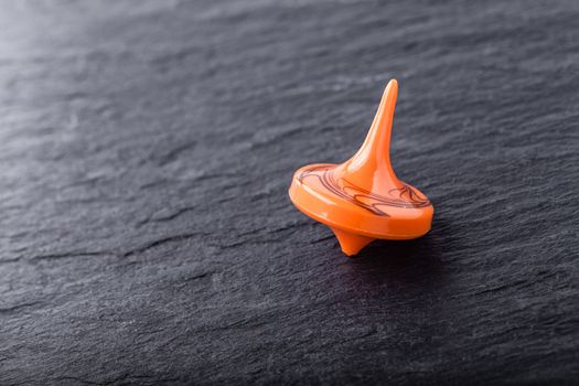 An orange Dreidel on a black background