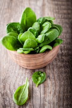 Baby spinach in the bowl on a wooden surface