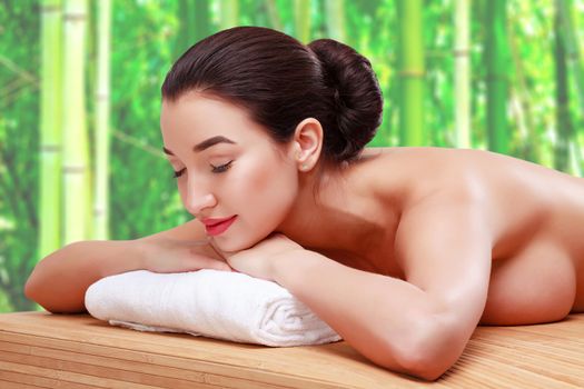 Young beautiful woman relaxing at spa salon in bamboo forest