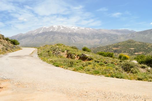 Winding road in the mountain of the center of Crete with the snowy ida mountain