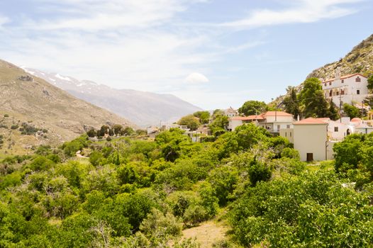 View of a small village Cretan and the snowy mountains and the greenery of the hills.