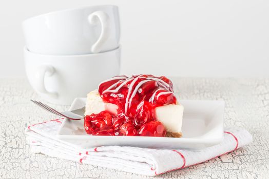 Slice of fresh cheesecake topped with a cherry glaze.