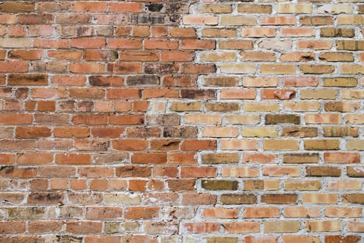 An old brick wall with two different colors of brick blending together.